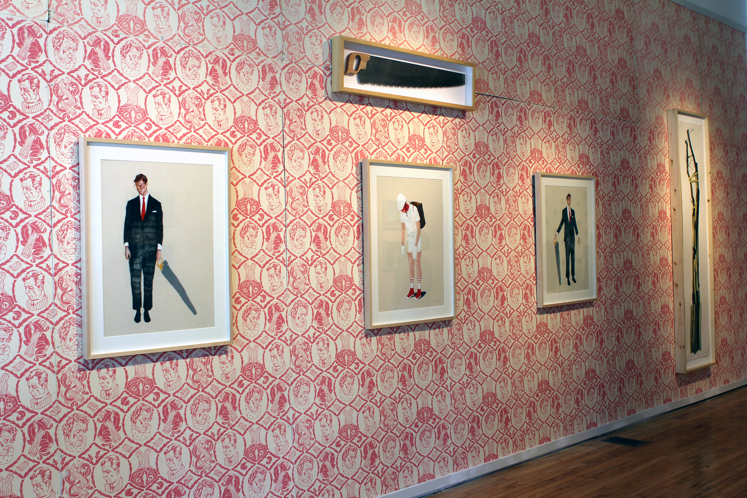 A photograph of tree paintings hanging in a gallery with pink, patterned wallpaper