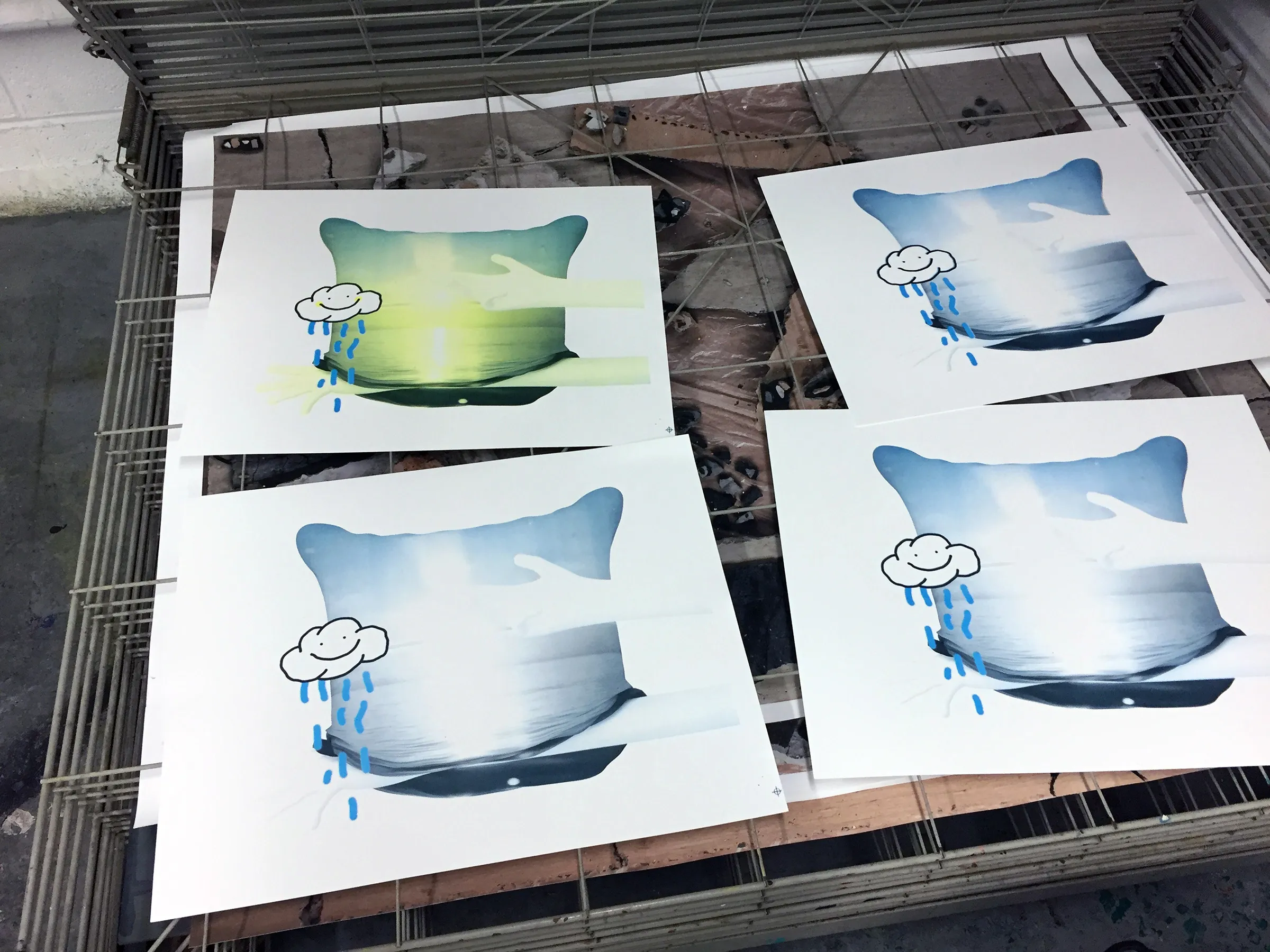 A photograph of four screen prints in a metal drying rack.