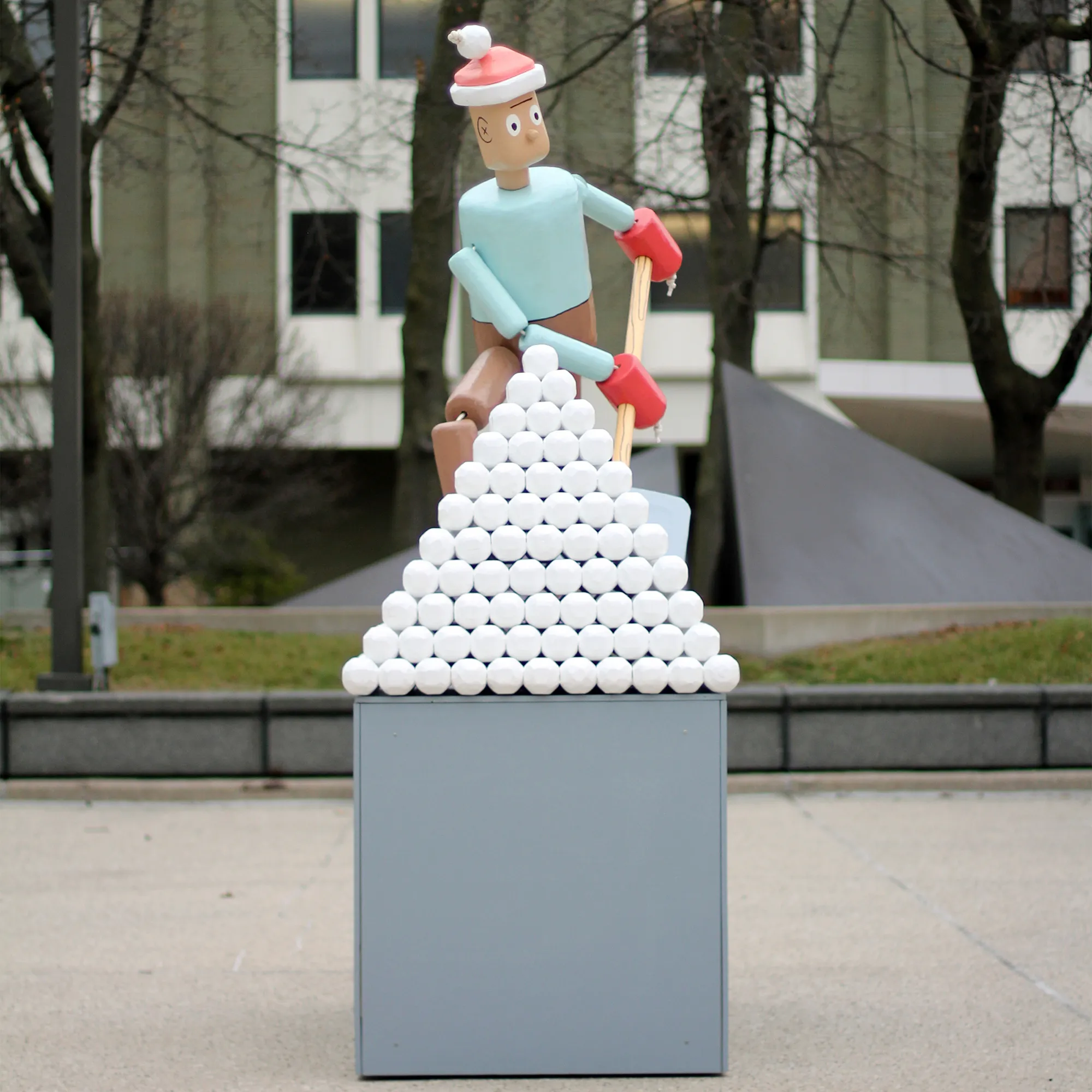a photograph showing a human-scale sculpture of a snow-shoveling push puppet from the front.