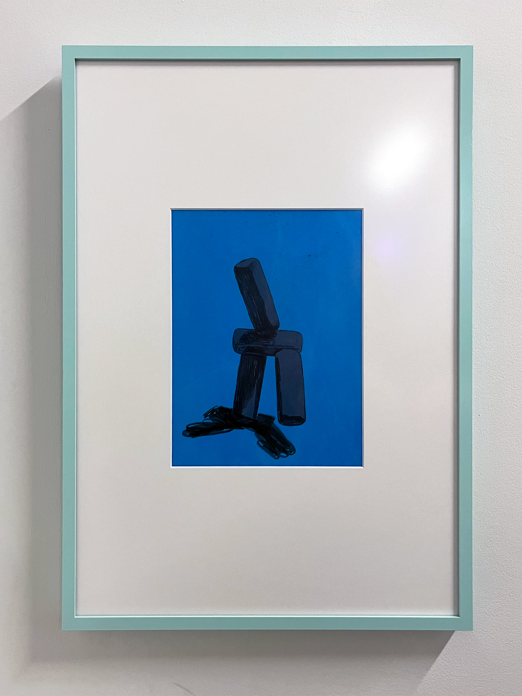 A photograph of a dark blue, abstract drawing with a white mat in a sky blue frame. The frame hangs on a white wall.